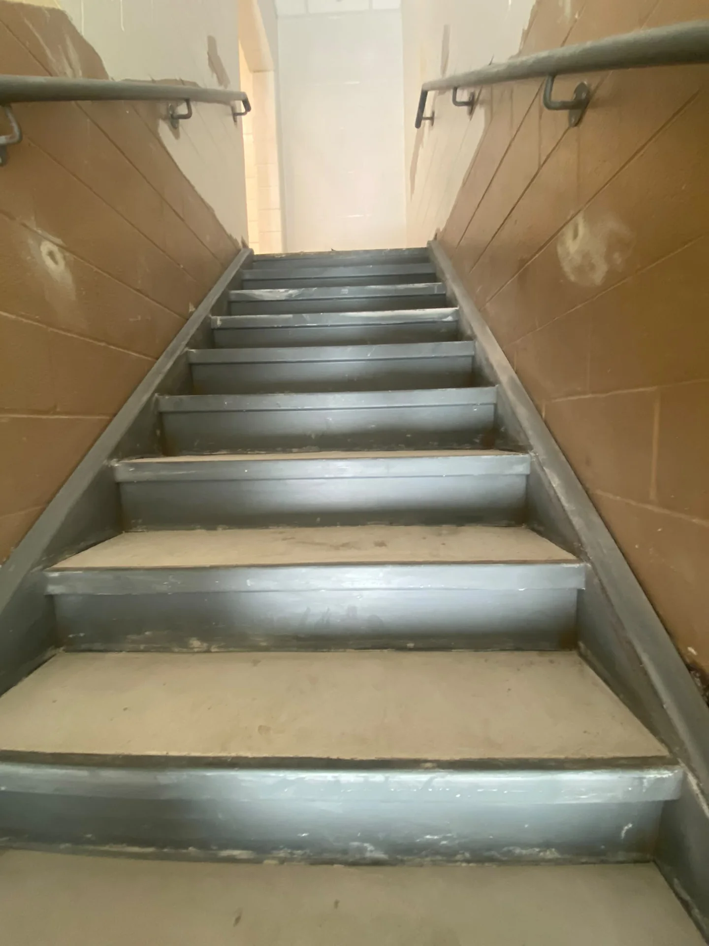 Before: brown stairwell block walls with visible patches and grey metal risers