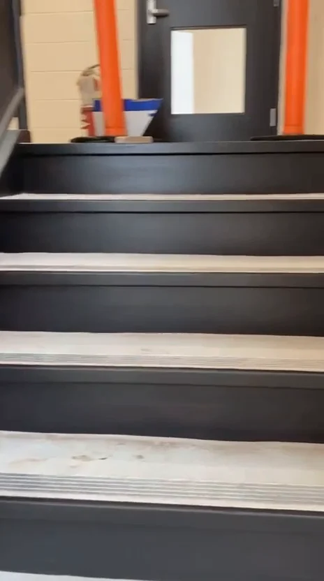 After: charcoal stair treads and risers beside the same handrail and metal nosings
