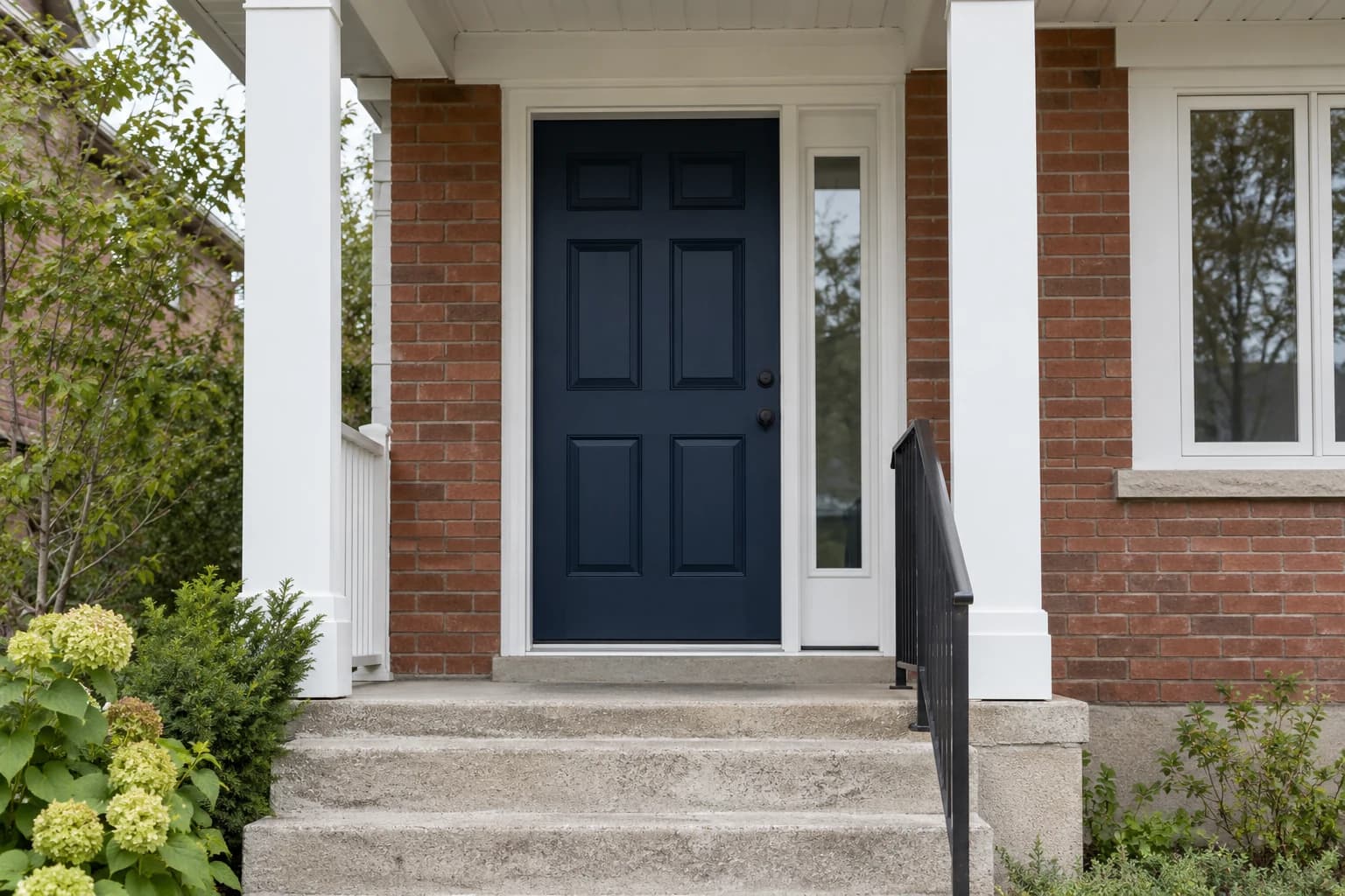 Brick porch with a navy front door and white painted posts and trim