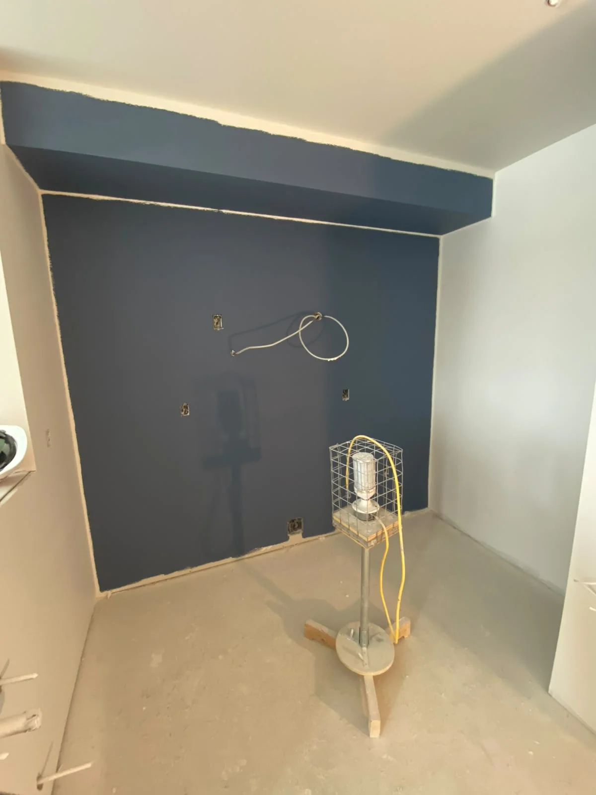 Deep blue accent wall and bulkhead above a covered floor with a standing fan