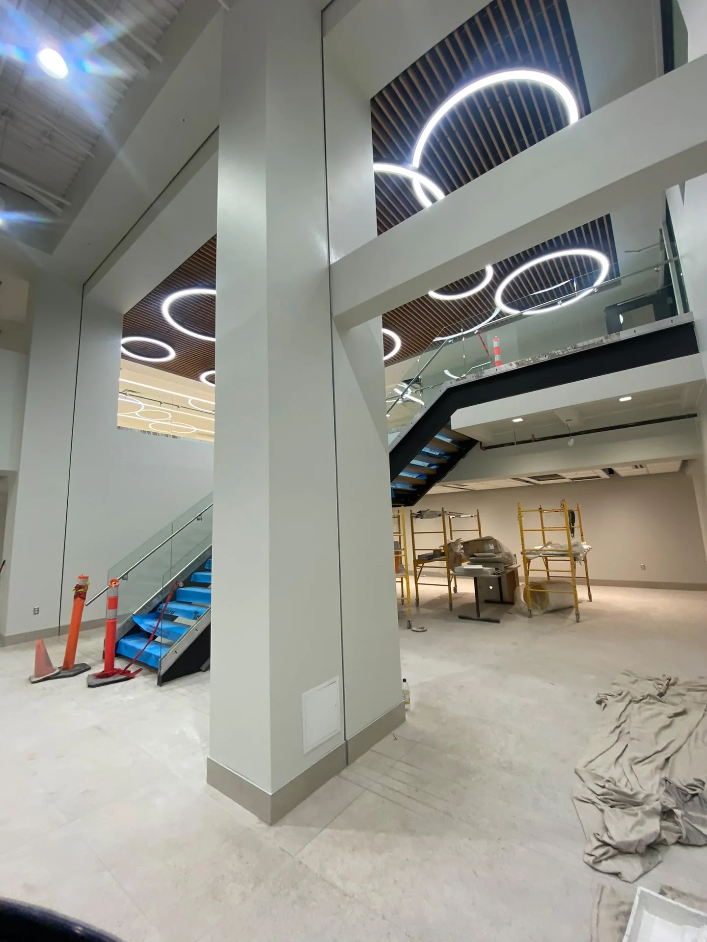 Light-painted columns beside an open commercial stair and ring-shaped ceiling lights