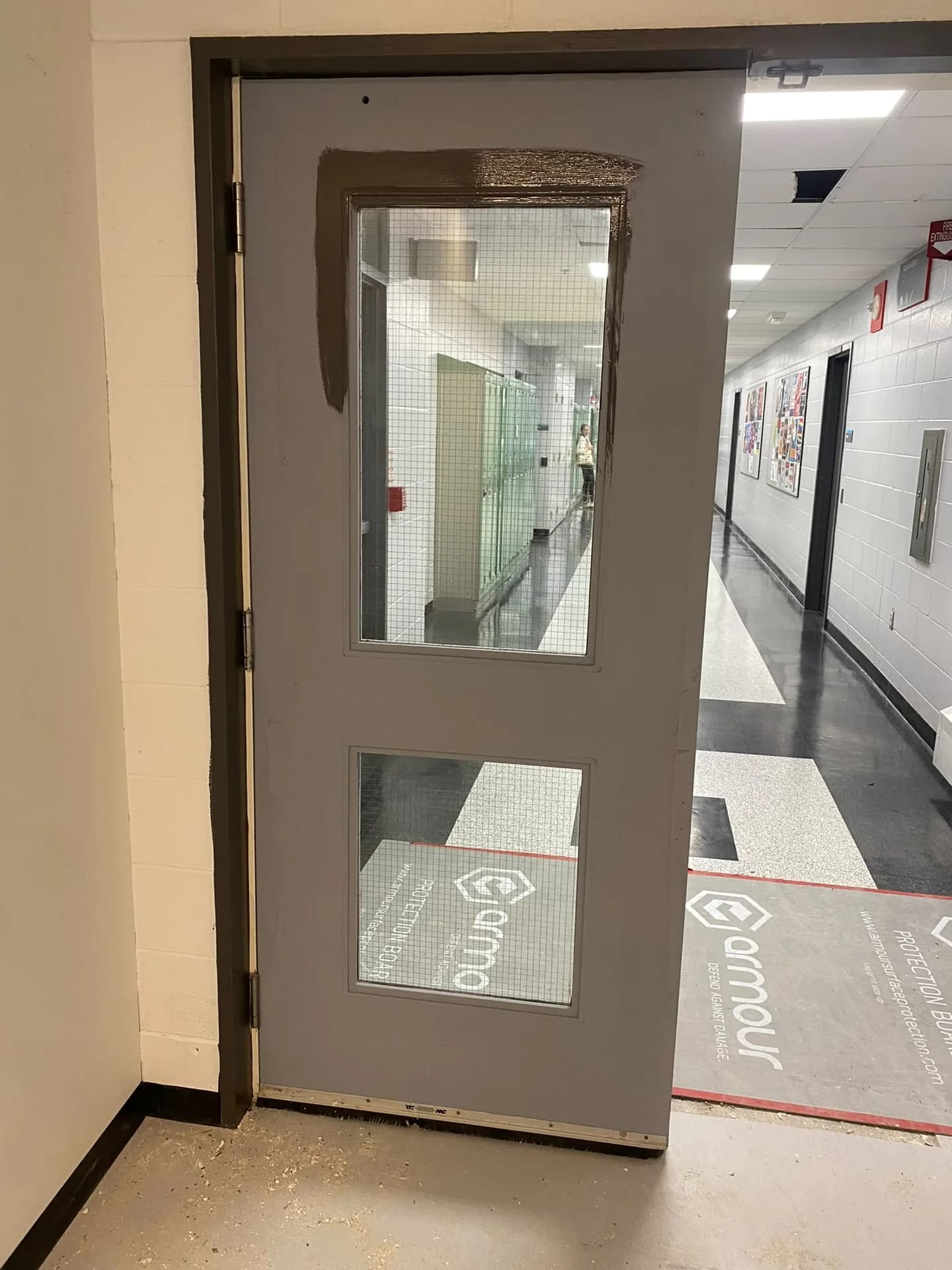 Open dark-painted glazed door beside a light corridor with protected flooring